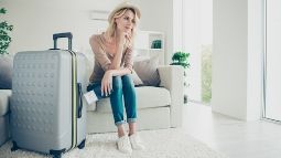 lady sitting on couch with boarding pass waiting with luggage