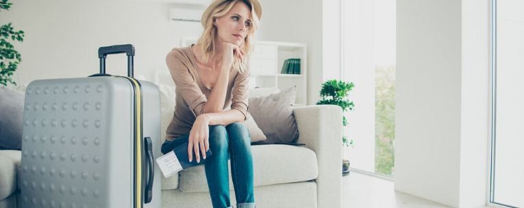 Allianz - lady sitting on couch with boarding pass waiting with luggage