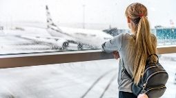 lady looking at airplane in snowstorm waiting departure