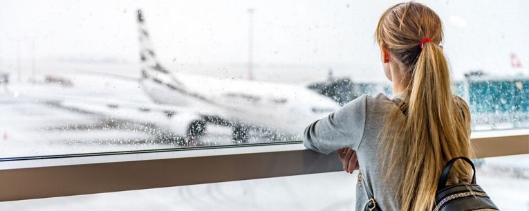 Allianz - lady looking at airplane in snowstorm waiting departure