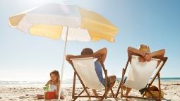 couple relaxing on the beach while daughter plays in the sand