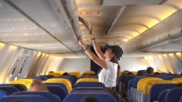 woman stowing away carryon bag on airplane