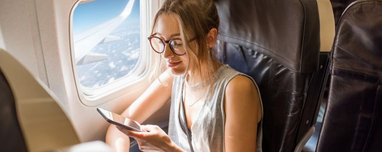 Allianz - traveler on airplane using phone