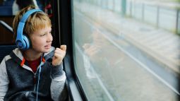 child with headphones on train