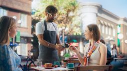 woman paying server at cafe while traveling abroad