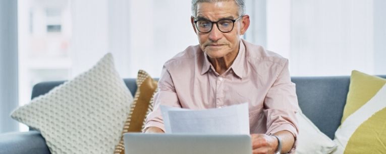 Allianz - senior man reviewing paperwork in front of laptop